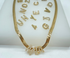 A gold herringbone chain necklace spells out the name Mia with diamond-encrusted letter charms, surrounded by other sparkly alphabet letter charms scattered on a white display.