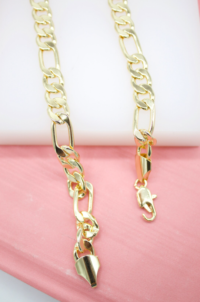 A gleaming gold Figaro chain necklace rests on a soft pink and white surface, highlighting its classic interlocking link design.