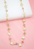 A delicate gold butterfly necklace with colorful crystal beads rests against a pink and white display background.