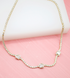 A delicate gold tennis necklace features a continuous line of sparkling diamonds set against a soft pink background.
