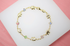 A gold chain bracelet features alternating elephant charms and colorful crystal beads arranged in a circle on a white display surface.