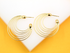 A pair of multi-strand gold hoop earrings rests against a white and yellow background.