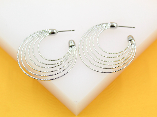 A pair of multi-strand silver hoop earrings rests on a white and yellow display stand.
