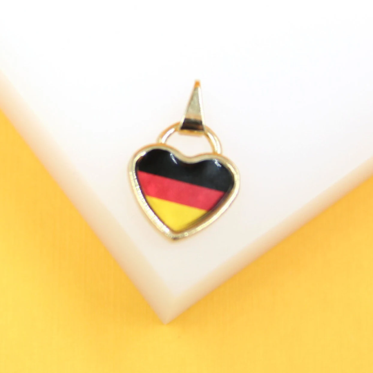 A gold heart-shaped pendant featuring the German flag rests on a white display surface.