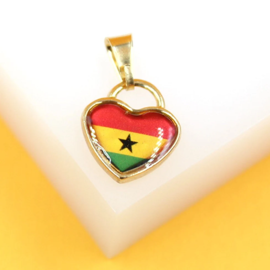 A gold-framed heart pendant displays the vibrant national flag of Ghana against a white and yellow background.