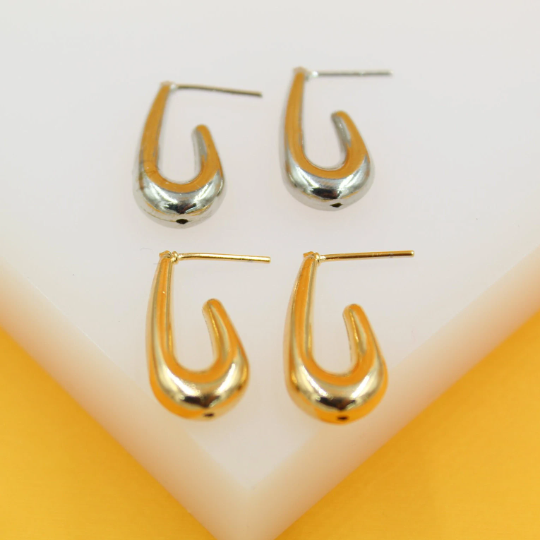 Two pairs of chic U-shaped stud earrings, one in silver-tone and the other in gold-tone, rest neatly on a white surface against a bright yellow background.
