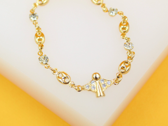 A delicate gold angel bracelet sparkles with embedded crystals against a light neutral background.