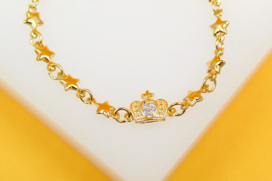 A delicate gold chain bracelet features alternating star charms and a sparkling crown centerpiece set with cubic zirconia stones.
