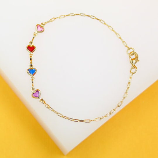 A delicate gold link bracelet features colorful heart charms displayed against a white and yellow surface.