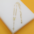 A delicate gold rosary necklace featuring bead chains, a central medallion, and a small cross rests on a white and yellow display surface.