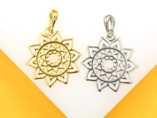 Two intricate mandala flower pendants, one gold and one silver, rest side by side against a white and orange background.
