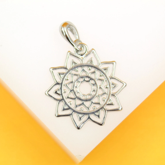 A silver mandala pendant rests against a white and yellow background.