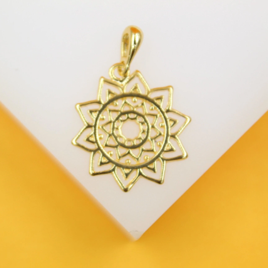A polished gold mandala pendant rests against a white and yellow display stand.