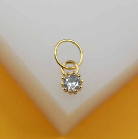 A delicate gold hoop earring features a sparkling cubic zirconia pendant centered on a white display block.