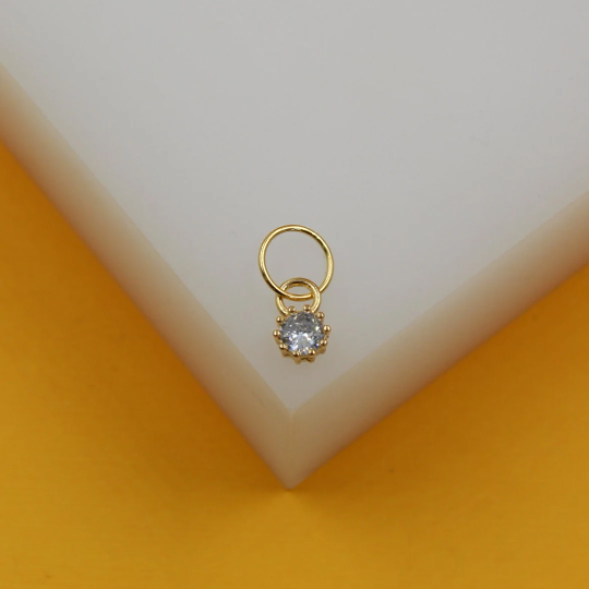A delicate gold charm pendant features a sparkling round cubic zirconia stone dangling from a small hoop ring.