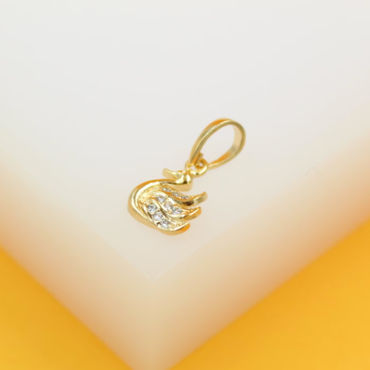 A delicate gold swan pendant sparkling with cubic zirconia stones rests on a white surface.