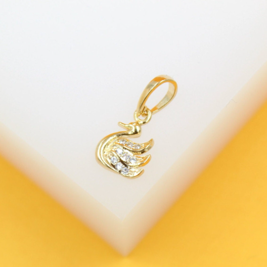 A sparkling gold swan pendant rests delicately on a white display surface.