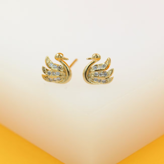 A pair of gold swan stud earrings sparkled with pave-set cubic zirconia crystals rests on a light background.
