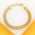 A delicate gold mesh bracelet rests on a white and yellow surface, showcasing its woven texture and lobster clasp.