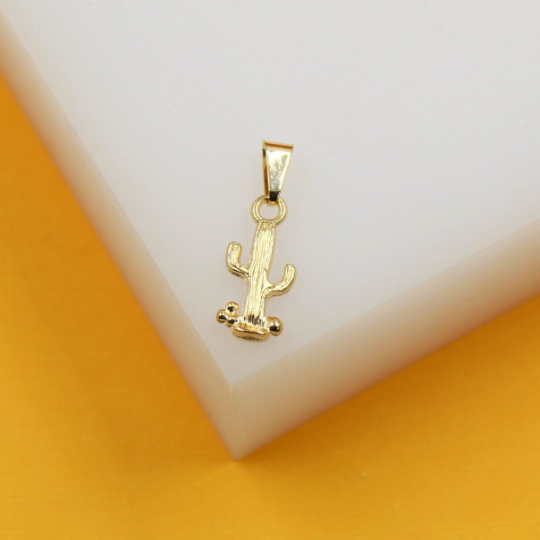 A shiny gold cactus pendant rests on a clean white display block against a vibrant yellow background.