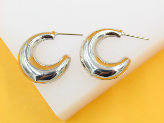 Two chunky silver hoop earrings rest against a clean white and yellow background.