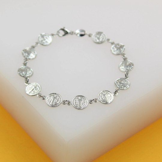 A silver Saint Benedict medal link bracelet rests on a white display block.