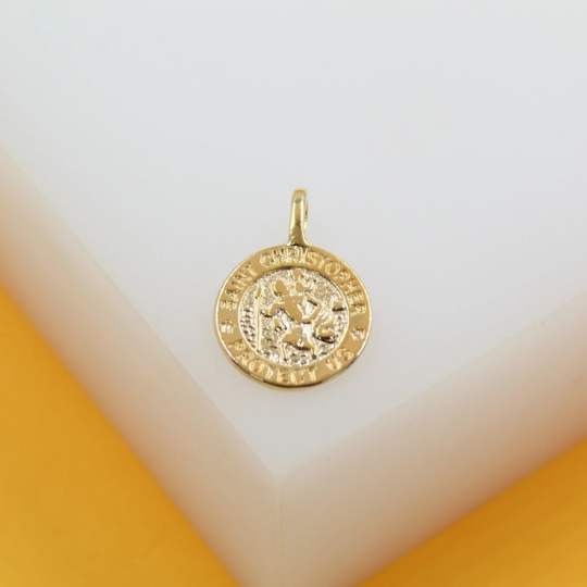 A gleaming gold Saint Christopher pendant rests on a minimalist white surface.