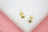 A pair of polished gold ball stud earrings rests against a white and pink background.