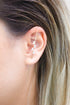 A woman wears a modern gold ear crawler with sparkling baguette-cut zirconia stones along her outer ear cartilage.