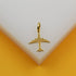 A shiny gold airplane pendant rests on a white display stand against a warm yellow background.