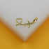 A gold airplane pendant with a heart-shaped trail rests on a white and yellow display surface.