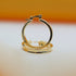 A pair of polished gold hoop earrings rests upright on a light surface against a soft orange and white background.