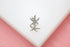 A sparkly silver starfish earring rests delicately on a white display against a soft pink background.