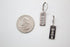 A pair of silver "Mama" drop earrings sits next to a US quarter coin for scale.