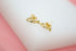 A pair of gold script love earrings sparkle on a white display surface.