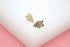 A pair of gold grape cluster stud earrings sparkle with embedded cubic zirconia stones on a white and pink surface.
