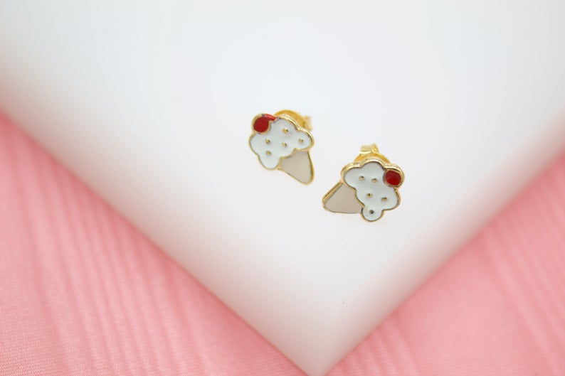 A pair of gold ice cream cone stud earrings features colorful enamel details on a white display surface.