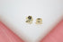 A pair of cute gold bird stud earrings resting on a white display surface.