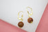 A pair of gold leverback earrings features dangling brown sandstone spherical beads.
