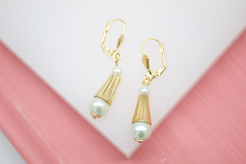 A pair of elegant gold leverback earrings feature dangling fluted cones and lustrous white pearls.