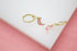 A pair of gold huggie hoop earrings features hanging pink enamel crescent moon charms accented with sparkling CZ stones.