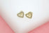 A pair of gold heart-shaped stud earrings features sparkling pave crystals and a cutout star detail in the center.