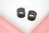A pair of sleek black pave huggie earrings rests on a white display surface.
