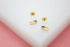 A pair of dainty gold stud earrings featuring delicate crystal stones rest on a white surface.