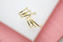 A modern gold multi-band ear cuff rests on a white and pink display surface.