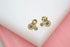 A pair of gold bicycle-shaped stud earrings featuring sparkling cubic zirconia stones rests on a white display block.