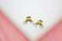A pair of gold rainbow and white cloud stud earrings rests on a white surface.