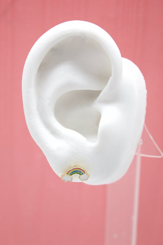 A white model ear displays a colorful enamel rainbow and cloud stud earring against a pink background.
