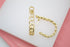 A pair of textured gold link hoop earrings rests on a white display surface.