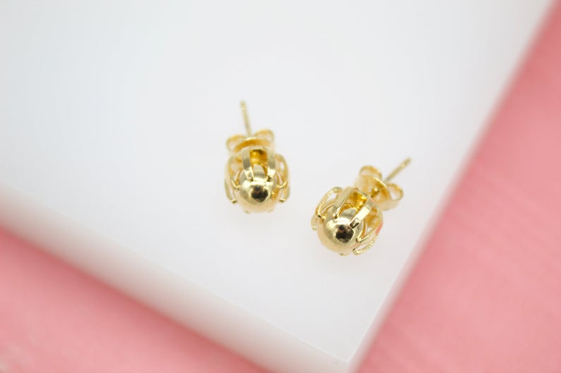 A pair of polished gold cage stud earrings rests on a white display surface.